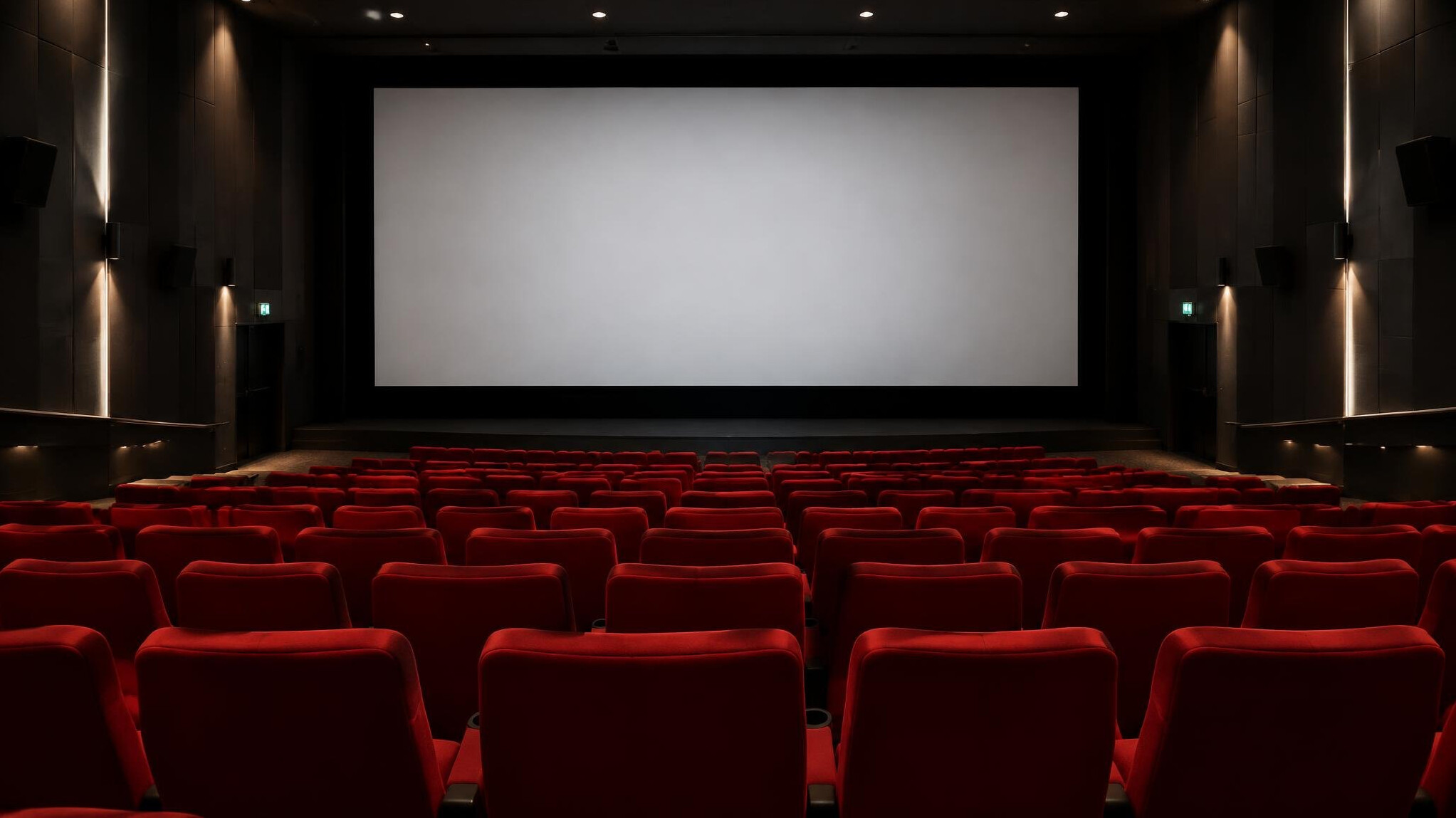 Empty cinema theater seats facing a large screen